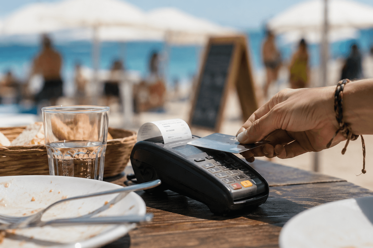 Paiement sans contact sur une terrasse de plage en été, carte présentée à un terminal