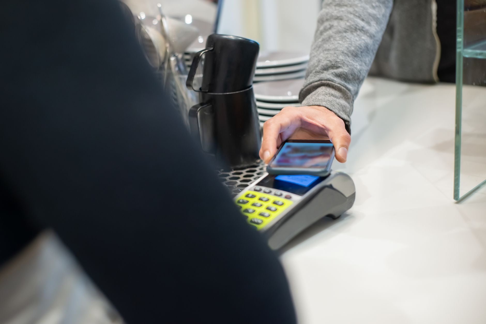 Client réglant sa commande au comptoir d'un café, geste répété du quotidien